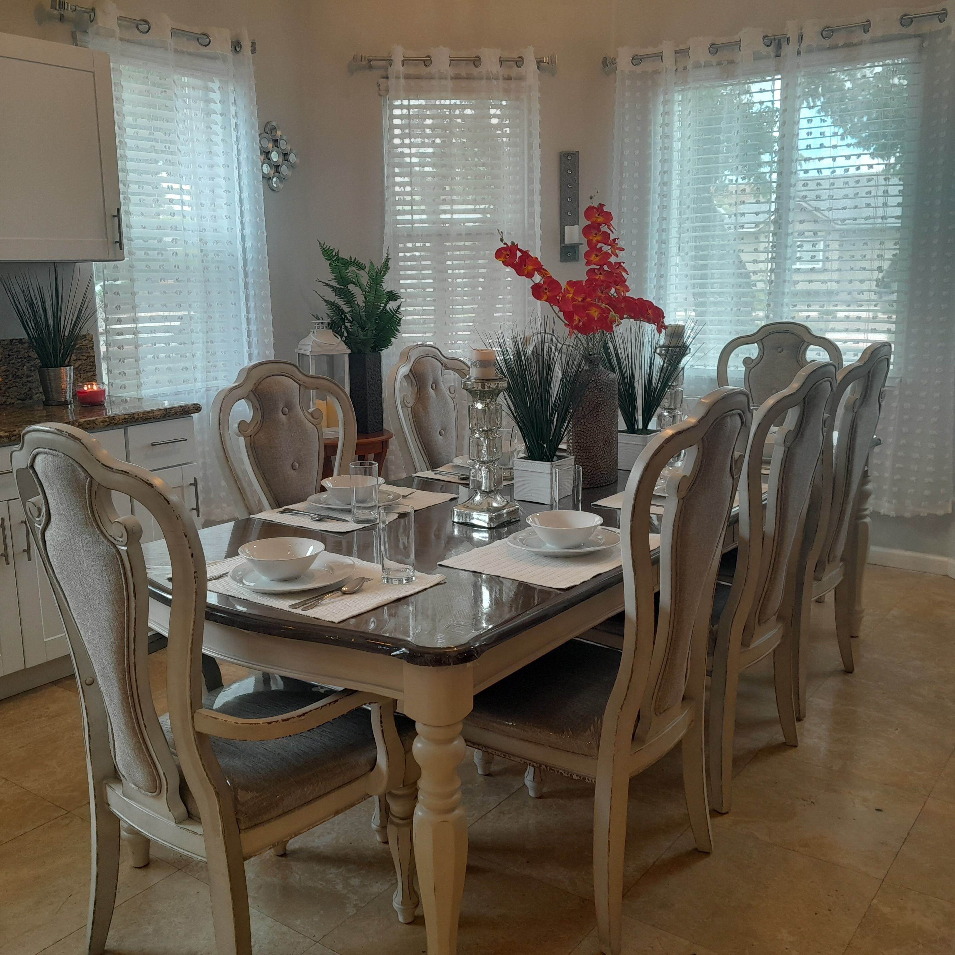 Un comedor con una mesa rectangular, seis sillas y una variedad de vajilla y objetos decorativos.