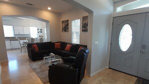 A spacious living room with a sectional sofa, a coffee table, and a rug. There is a kitchen in the background with white cabinets and a dining area. - Luxe 6Bd/6Ba,5 Minutes Disney Convention C, Beaches 20minutes


















 (Anaheim)