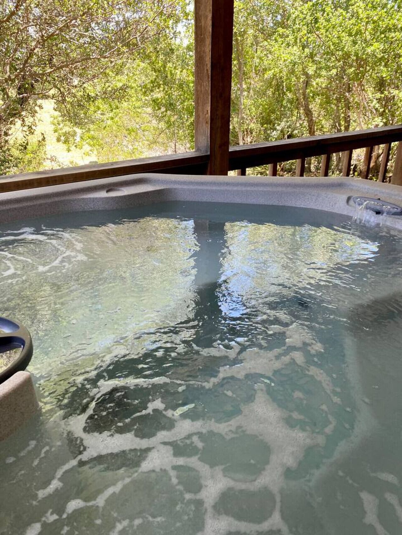 Ein Whirlpool mit einer Holzterrasse und Blick auf Bäume.