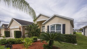 A two-story house with a front yard featuring a palm tree, a well-maintained lawn, and a brick chimney. - Family Disney Villa w/private pool 15 min to Parks (Davenport)