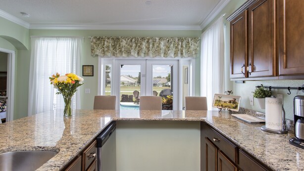 A kitchen with granite countertops, wooden cabinets, and a view of the backyard. - Family Disney Villa w/private pool 15 min to Parks (Davenport)