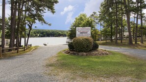 A beach sign with restrictions and a view of a lake surrounded by trees.