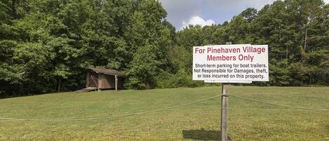 A sign for Pinehaven Village Members Only with a wooden structure in the background.