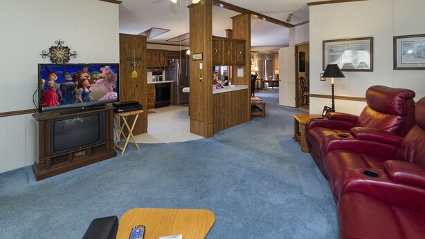 A living room with a television, a red leather sofa, and a small wooden table.