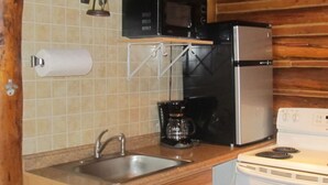 A compact kitchen with a stainless steel sink, a black microwave, a white refrigerator, and a white stove. - The Benjamen - Newly Remodeled Great Views (Cody)