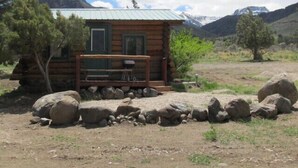 A rustic cabin with a metal roof, wooden walls, and a small porch. - The Benjamen - Newly Remodeled Great Views (Cody)