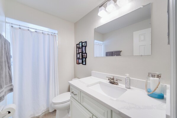 Une salle de bain avec un lavabo blanc, un miroir et des toilettes.
