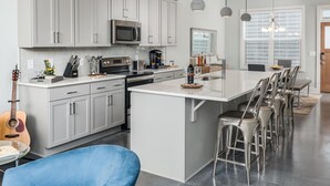 A modern kitchen with grey cabinets, a stainless steel microwave, and a large island with bar stools. - Skyline Retreat  Minutes To Downtown + Free Parking (Nashville)