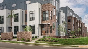 A modern apartment building with a mix of brick and siding exteriors, multiple windows, and a well-maintained lawn. - Skyline Retreat  Minutes To Downtown + Free Parking (Nashville)