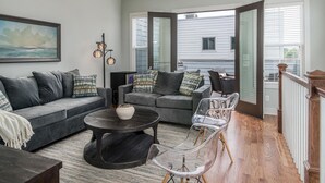 A cozy living room with a gray sofa, a round coffee table, and a clear chair. There is a painting on the wall and a window with blinds. - Skyline Retreat  Minutes To Downtown + Free Parking (Nashville)