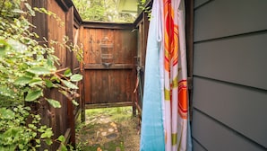 A wooden door leading to a covered outdoor area with a metal rack and a blue and white curtain.