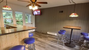 A kitchen with a wooden countertop, blue bar stools, a central island, and a ceiling fan.