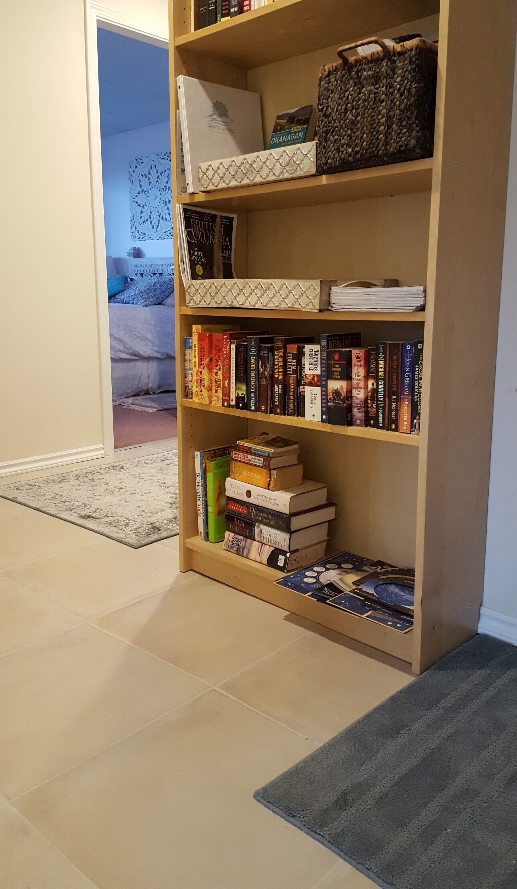 Une bibliothèque contenant divers ouvrages et un panier décoratif.