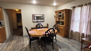 A dining area with a wooden table, chairs, a rug, a cabinet, and a mirror on the wall. - 1109 S. Boston Pl 3 bedroom, 2 bath house (Russellville)