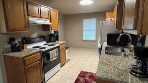 A kitchen with wooden cabinets, a stove, a refrigerator, and granite countertops. - 1109 S. Boston Pl 3 bedroom, 2 bath house (Russellville)