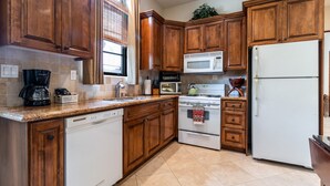 A kitchen with wooden cabinets, a white dishwasher, a stove, a microwave, and a refrigerator. - Charming, Elegant, Luxury, Walk to Moonlight Beach & Downtown (Encinitas)