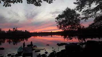 Fredfyldt søscene ved solnedgang, stille vand og en dock med kajakker.