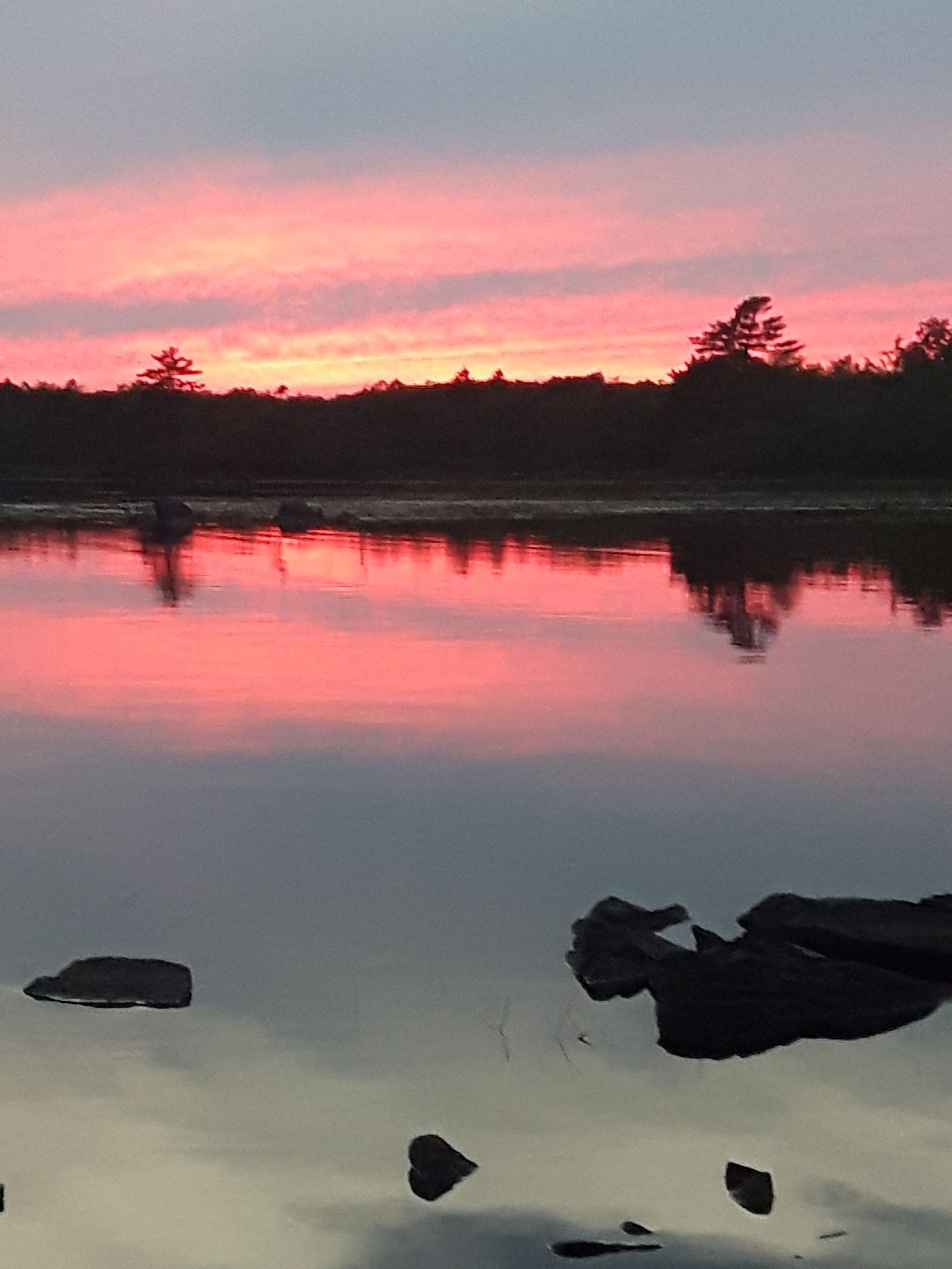 A calm lake with a reflection of the sky.