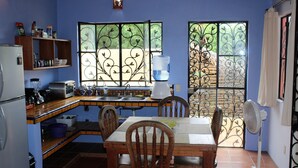 A compact kitchen with a dining table, chairs, a water dispenser, and a fan. - Casita Tortuga, spacious 1BR1BA, roof terrace w view, walking dist to beach&town (Sayulita)