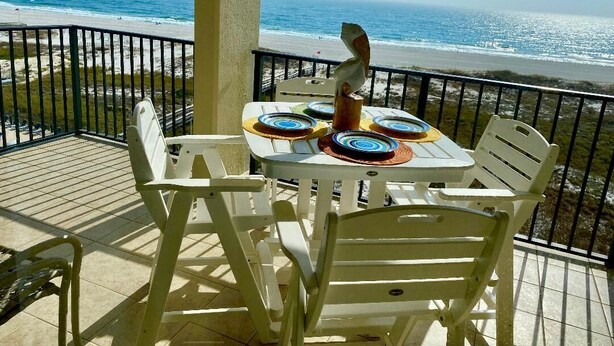 Un balcon avec une table et des chaises, donnant sur une plage.