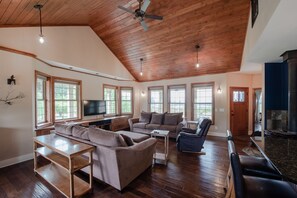 A spacious living room with a high ceiling, wooden floors, and large windows. - Beautiful house and private apartment, hot tub & sauna, 6 miles from Hood River! (White Salmon)