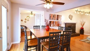 A dining area with a wooden table and chairs, a ceiling fan, and a fireplace. - 5 bdrm Near Belmar: Dining, Shops, Movie Theater, and Entertainment. Great for Red Rocks, Downtown, and Mountain Visits! (Lakewood)