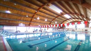 An indoor swimming pool with multiple lanes, a wooden ceiling, and red flags. - 5 bdrm Near Belmar: Dining, Shops, Movie Theater, and Entertainment. Great for Red Rocks, Downtown, and Mountain Visits! (Lakewood)