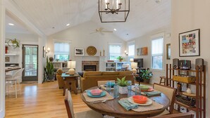 Un salón espacioso con chimenea, un comedor con una mesa redonda y una cocina al fondo.