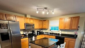 A modern kitchen with wooden cabinets, stainless steel appliances, and a central island with bar stools. - 3BR/2.5BA Eden Ridge, Great Location for Bethel & Sunday River (Bethel)
