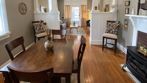 A dining area with a wooden table and chairs, a ceiling fan, and a fireplace.
