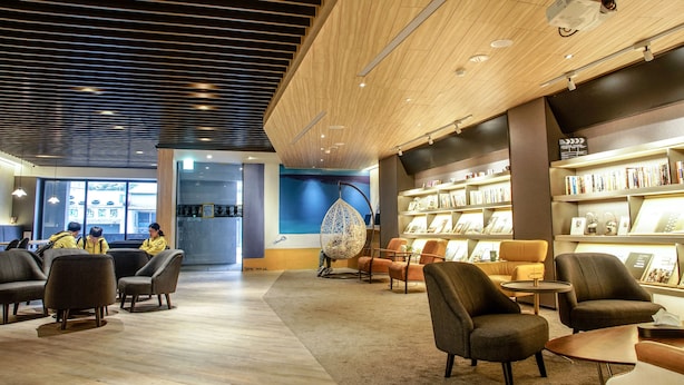 A modern interior with seating areas, a projector, and bookshelves. - Hub Hotel (Taoyuan City)