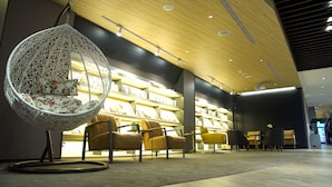 A modern library with a hanging chair, bookshelves, and comfortable seating areas. - Hub Hotel (Taoyuan City)