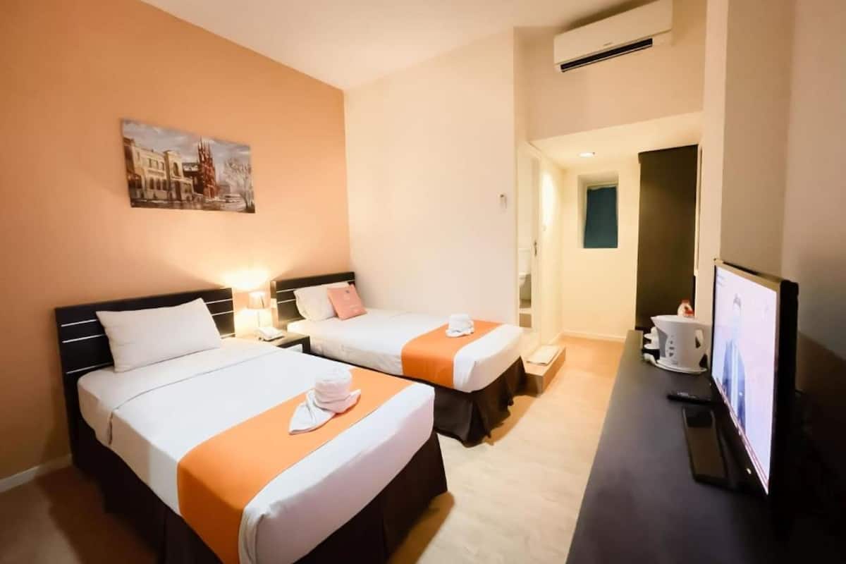 A hotel room with two beds, a television, and a painting on the wall.