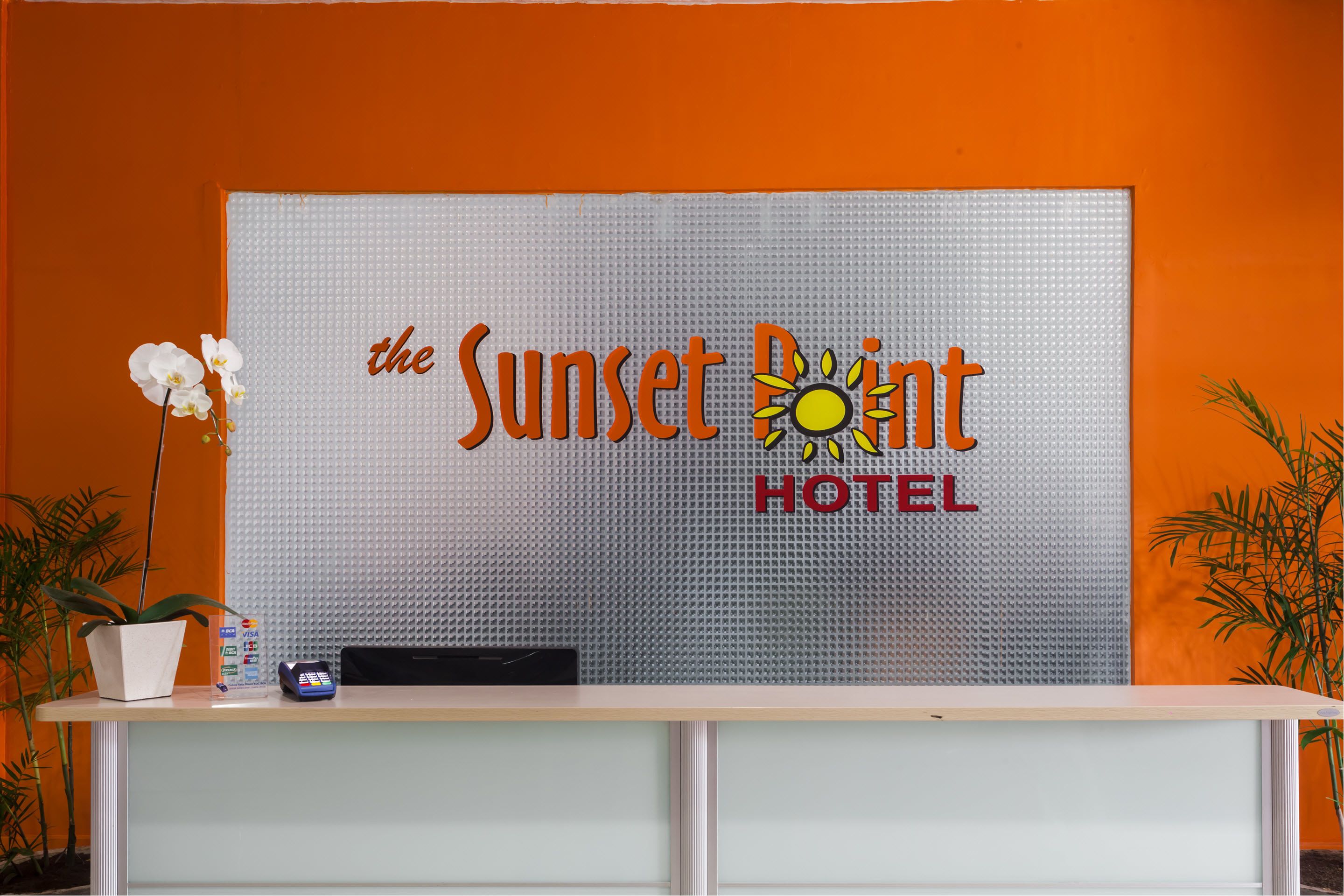 A reception desk with a sign reading "the Sunset Point HOTEL" and a logo of a sun.