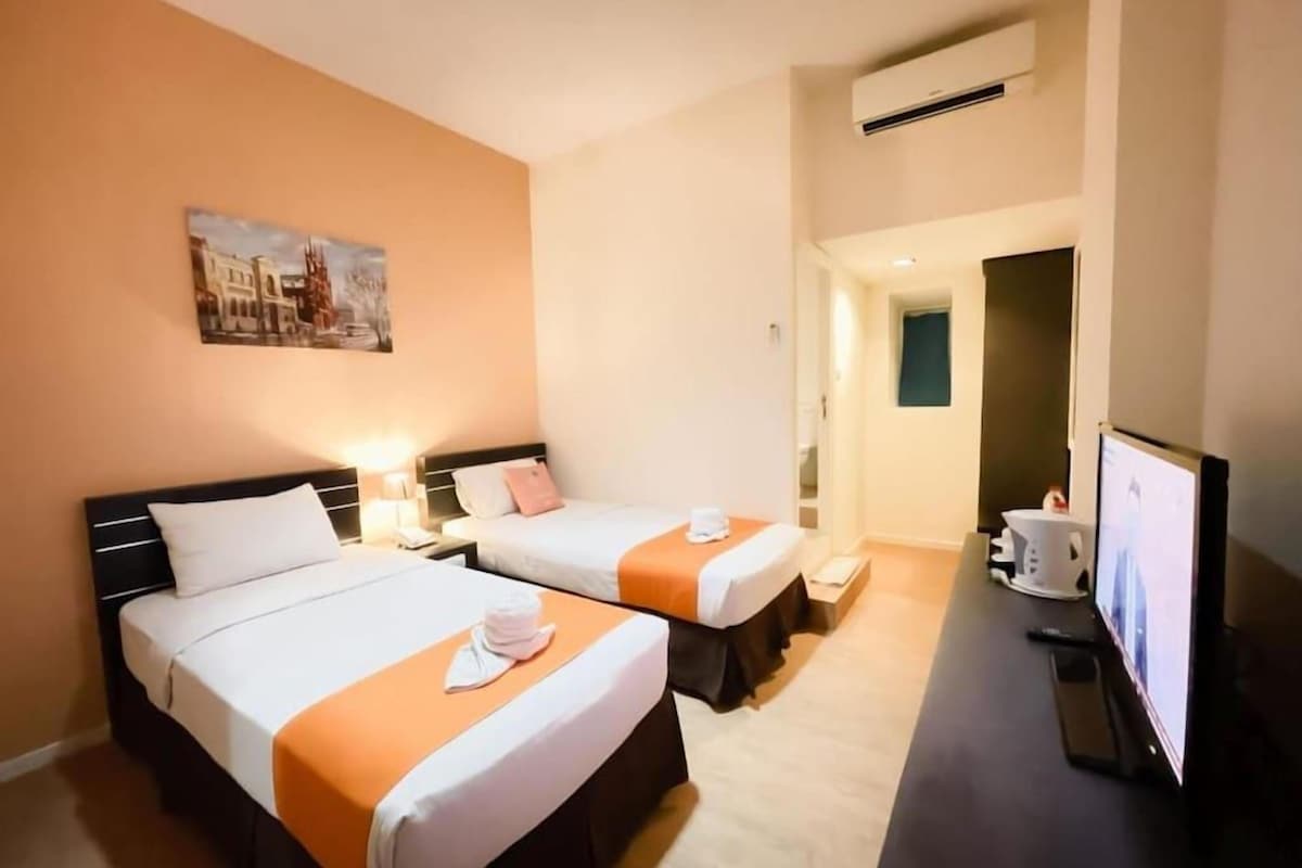 A hotel room with two beds, a television, and a painting on the wall.