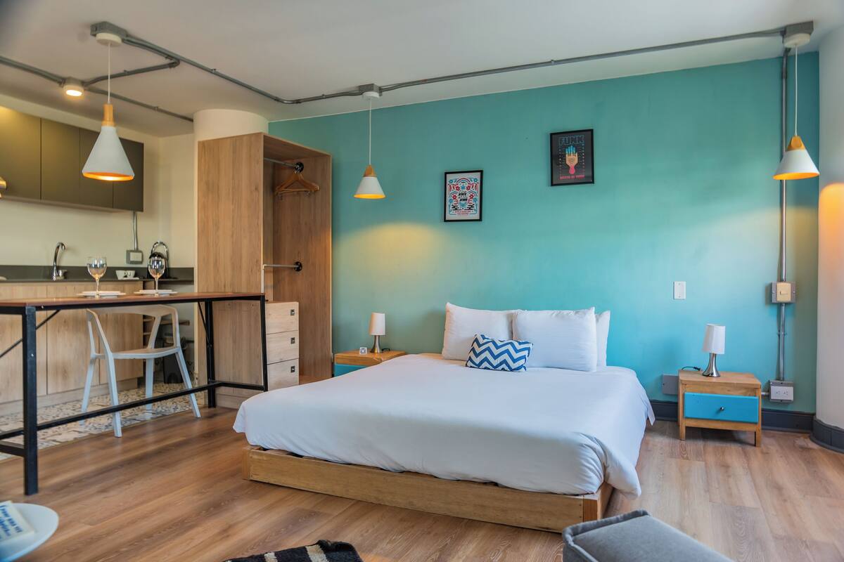A modern bedroom with a bed, bedside tables, a desk, and a chair.