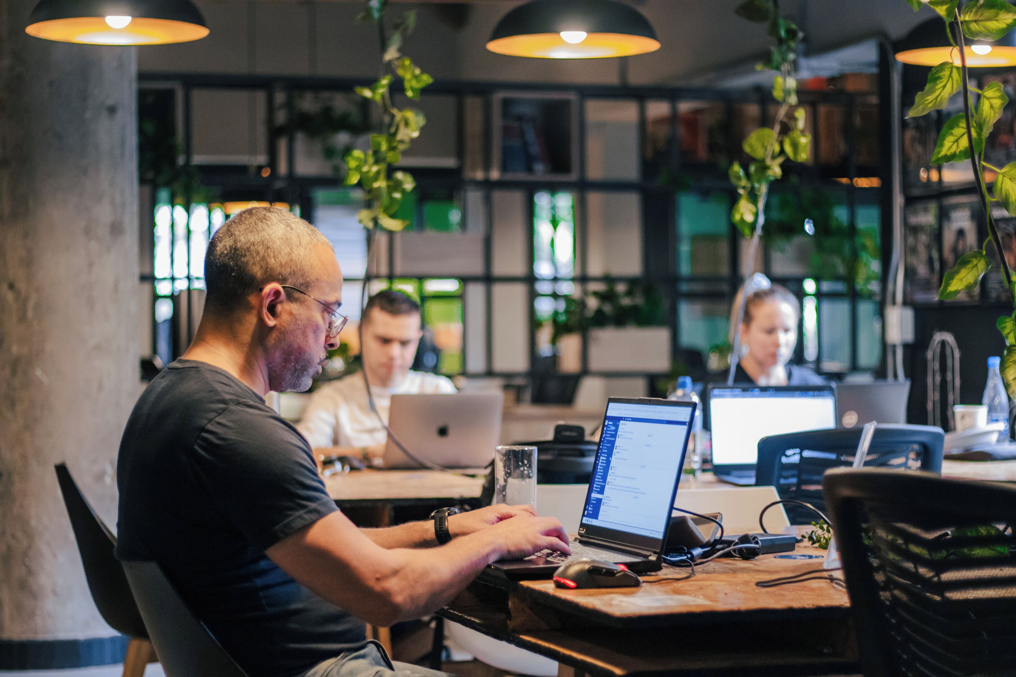 A modern workspace with multiple people working on laptops.
