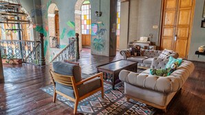 A spacious living area with a wooden staircase, a sofa, a coffee table, and a patterned rug. - Delgadillo Boutique Hotel by Socialtel (Bogotá)