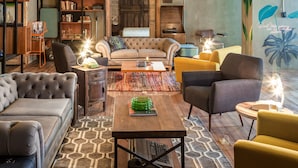 A modern living room with a sofa, armchairs, a coffee table, and a bookshelf. - Delgadillo Boutique Hotel by Socialtel (Bogotá)