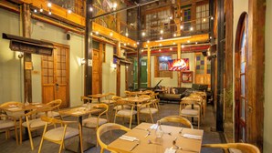 A restaurant with wooden furniture, multiple dining tables, and a neon sign. - Delgadillo Boutique Hotel by Socialtel (Bogotá)