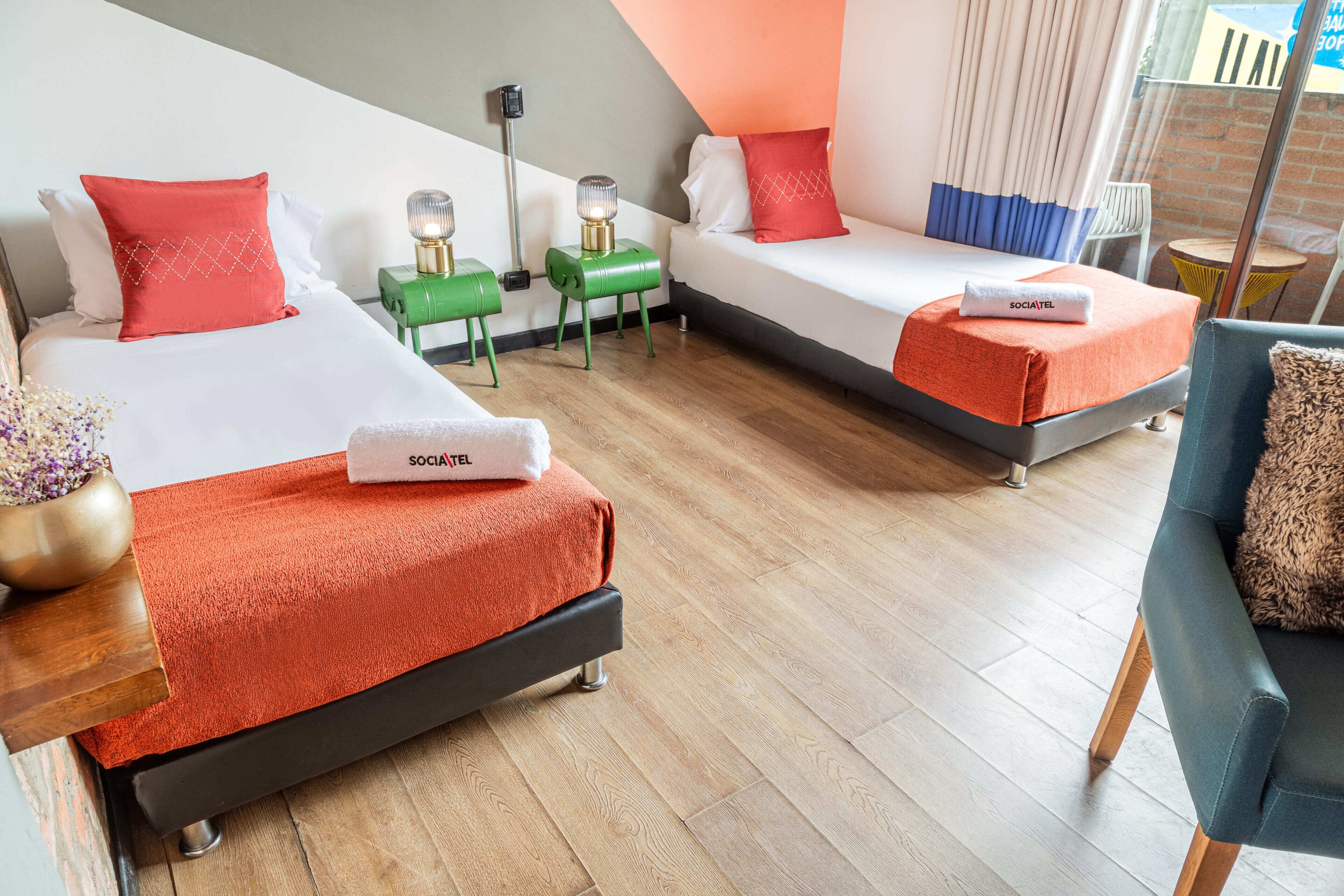 Une chambre d’hôtel avec deux lits, une petite table, une chaise et une vue sur l’extérieur.