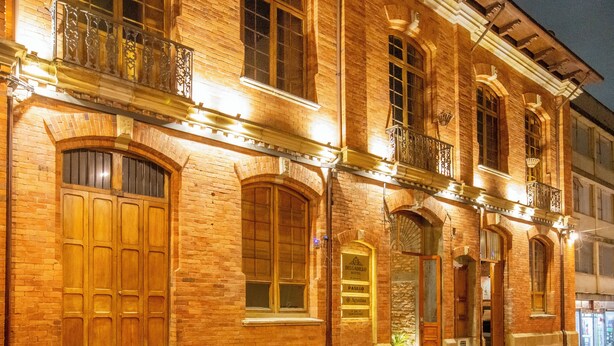 A brick building with a large wooden door, multiple windows, and a balcony with ornate railings. - Delgadillo Boutique Hotel by Socialtel (Bogotá)
