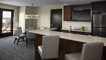A modern kitchen with a large island, dark wooden cabinets, and a stainless steel refrigerator.
