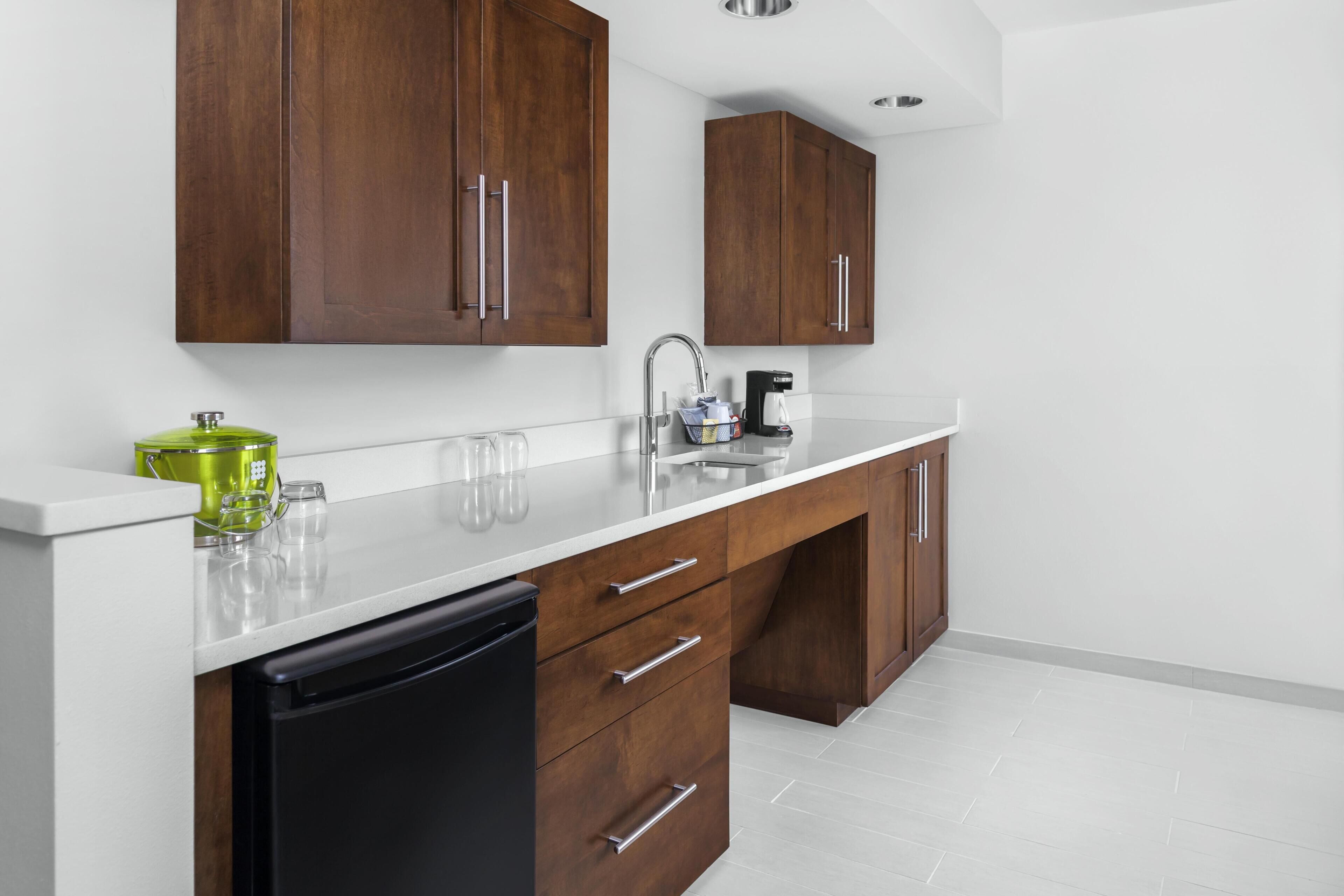 A modern kitchen with wooden cabinets, a white countertop, and a black dishwasher.