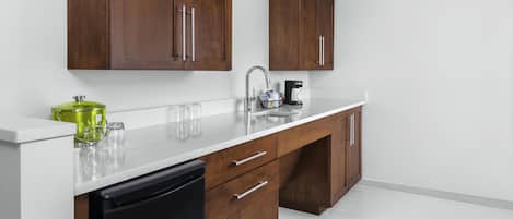 A modern kitchen with wooden cabinets, a white countertop, and a black dishwasher.