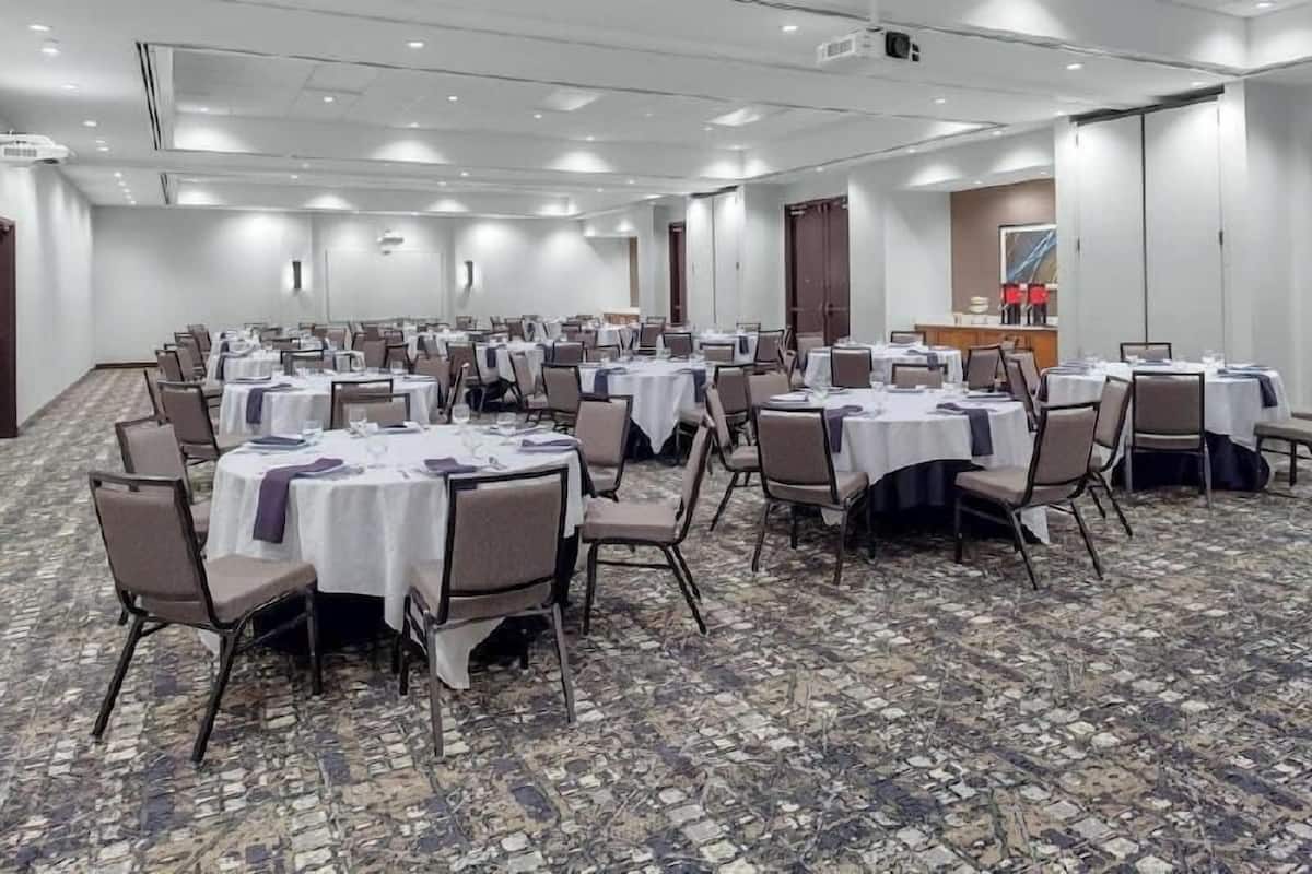 Una sala de conferencias con mesas redondas, sillas y piso alfombrado.