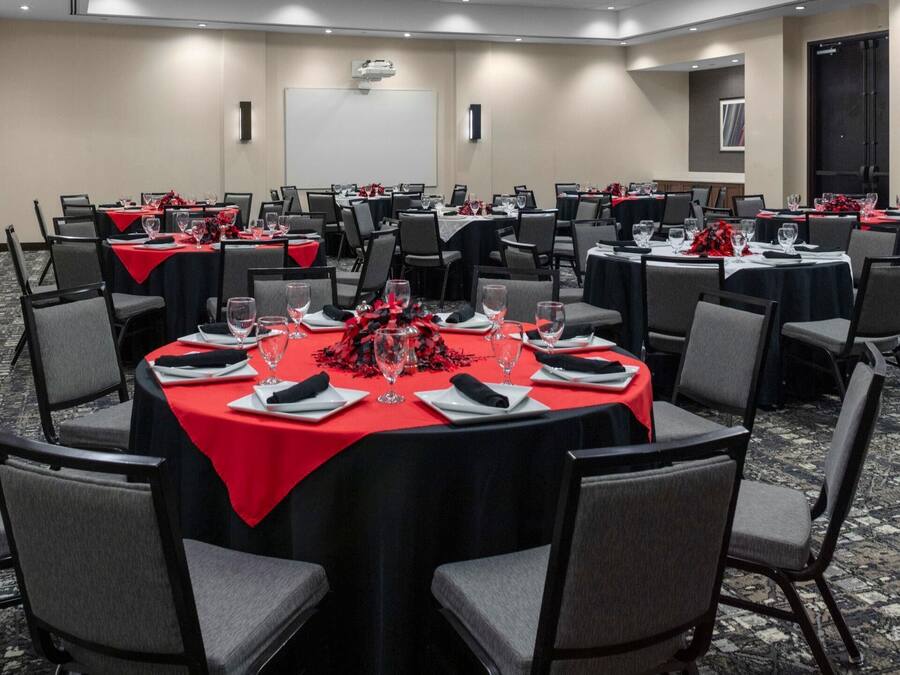 A conference room with multiple tables, each set with plates, glasses, and red tablecloths.