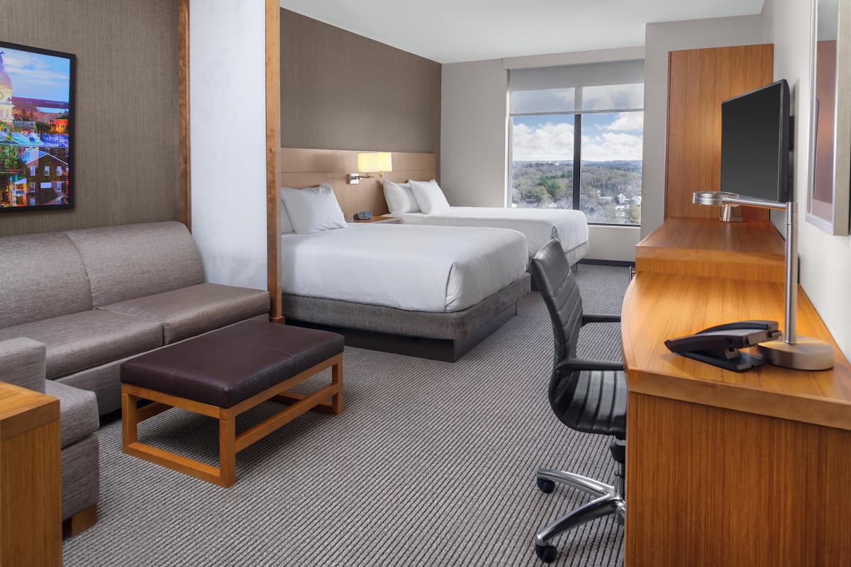 Habitación de hotel con sofá, dos camas, escritorio y televisión.