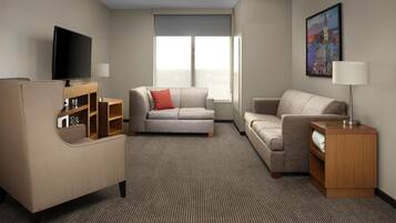 A hotel room with a flat-screen TV, two sofas, a wooden side table, and a painting on the wall.