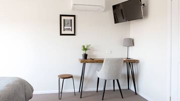 A small, modern room with a desk, chair, and a television mounted on the wall.